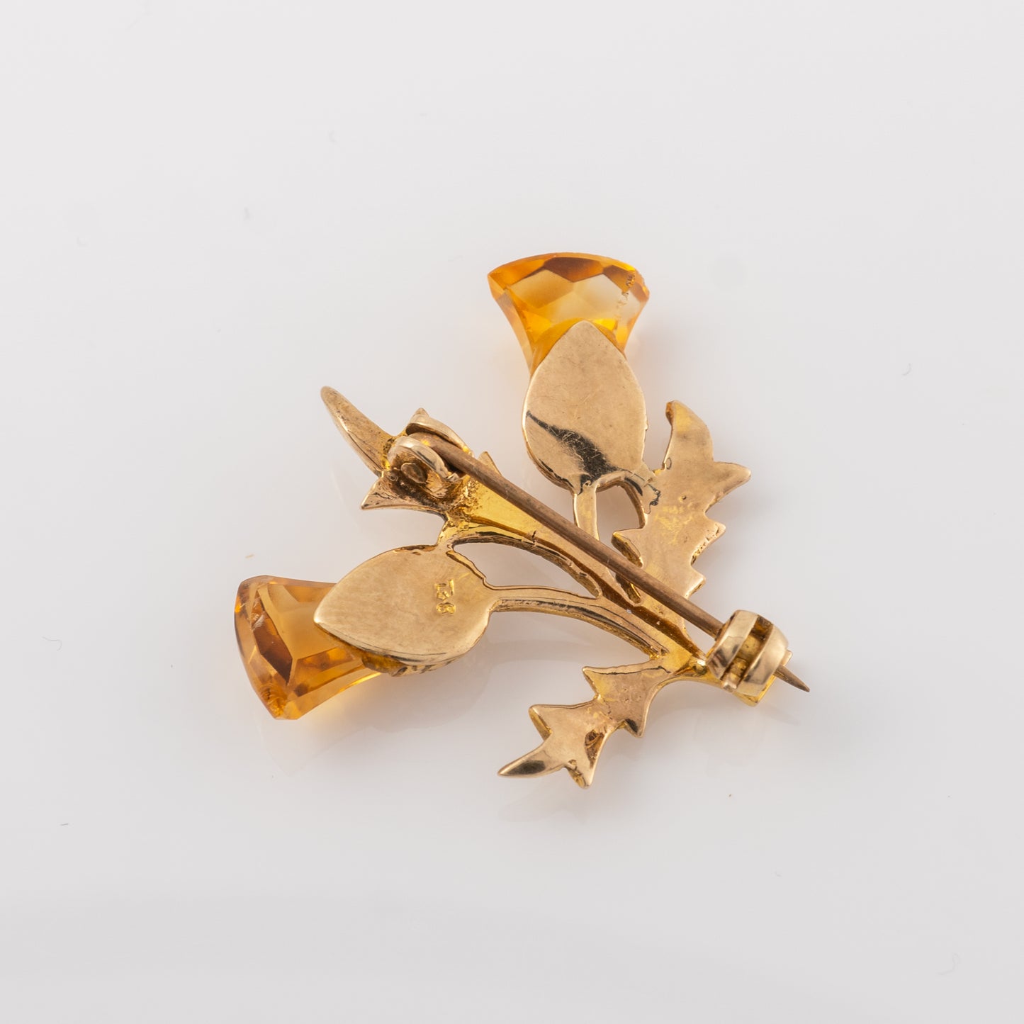 Reverse side of a vintage gold thistle brooch with citrine gemstones, showing the pin clasp