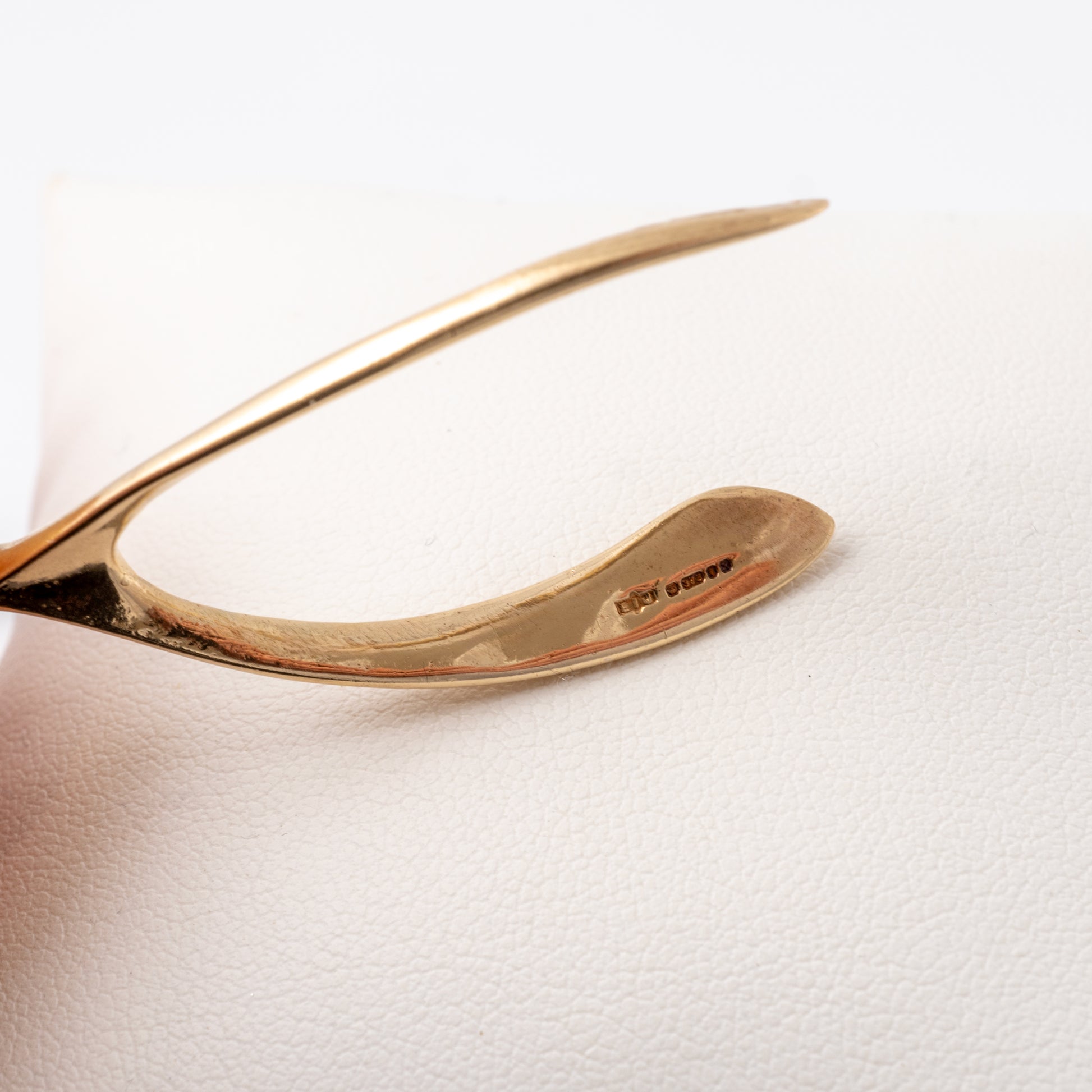 Solid gold wishbone pendant showcasing vintage hallmarks inside the curve of the design