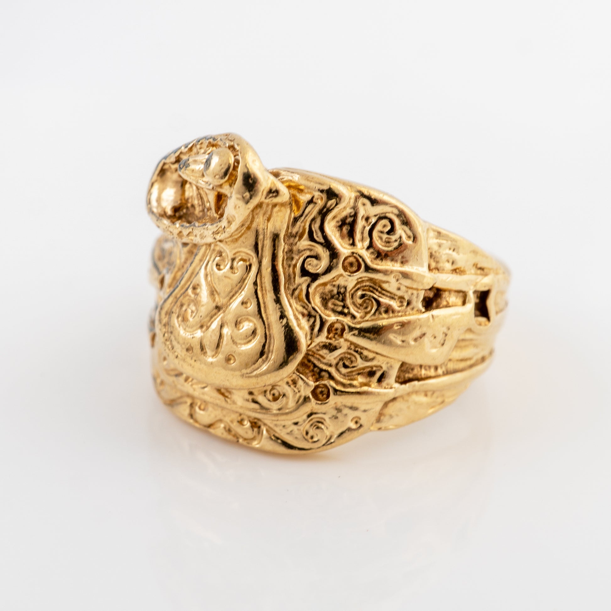 Close-up of the raised serpent detail on a vintage men's 9ct gold saddle ring with ornate scrollwork.