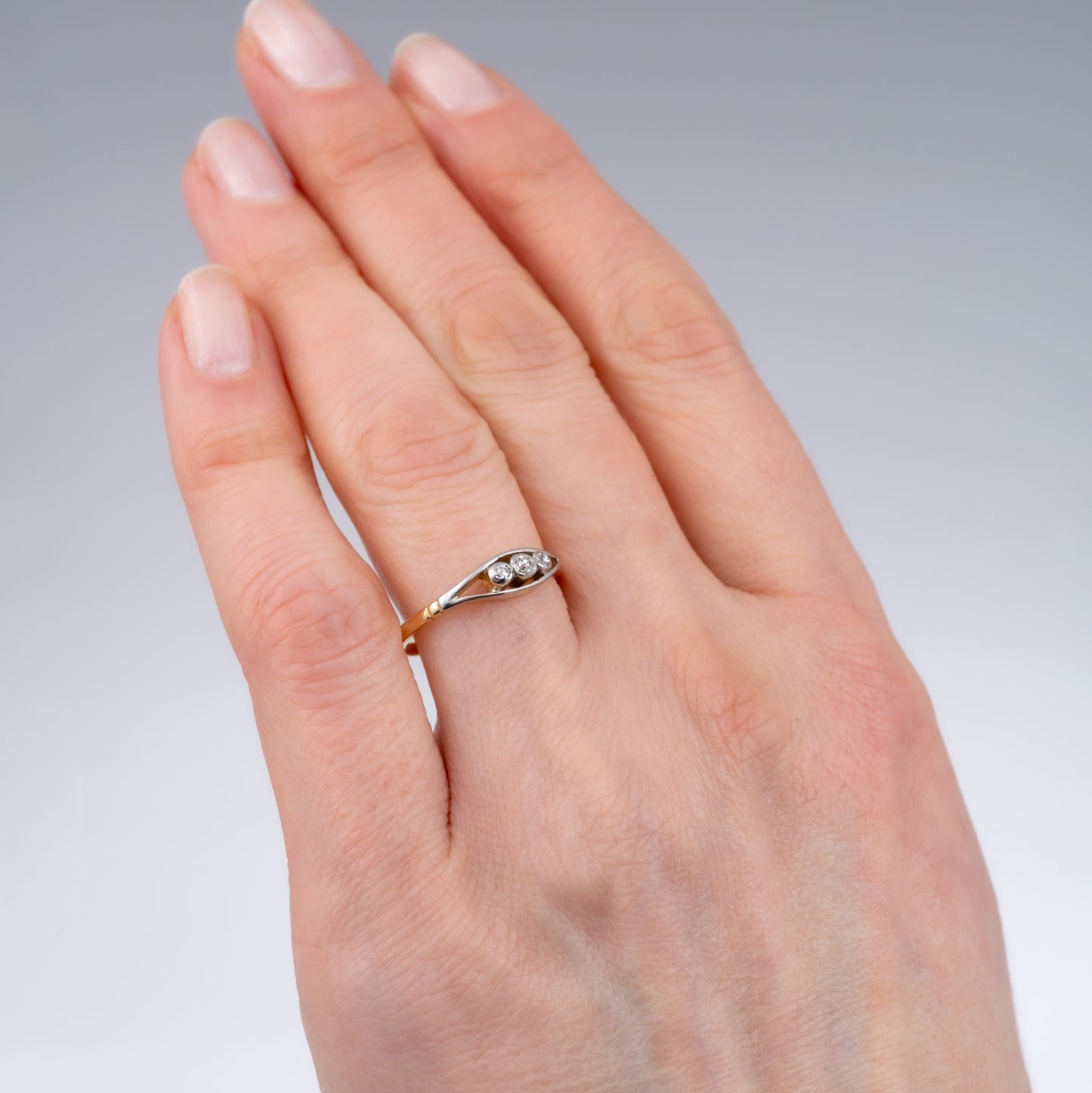 Vintage three-stone diamond ring in 18ct gold, worn on hand, showing elegant design