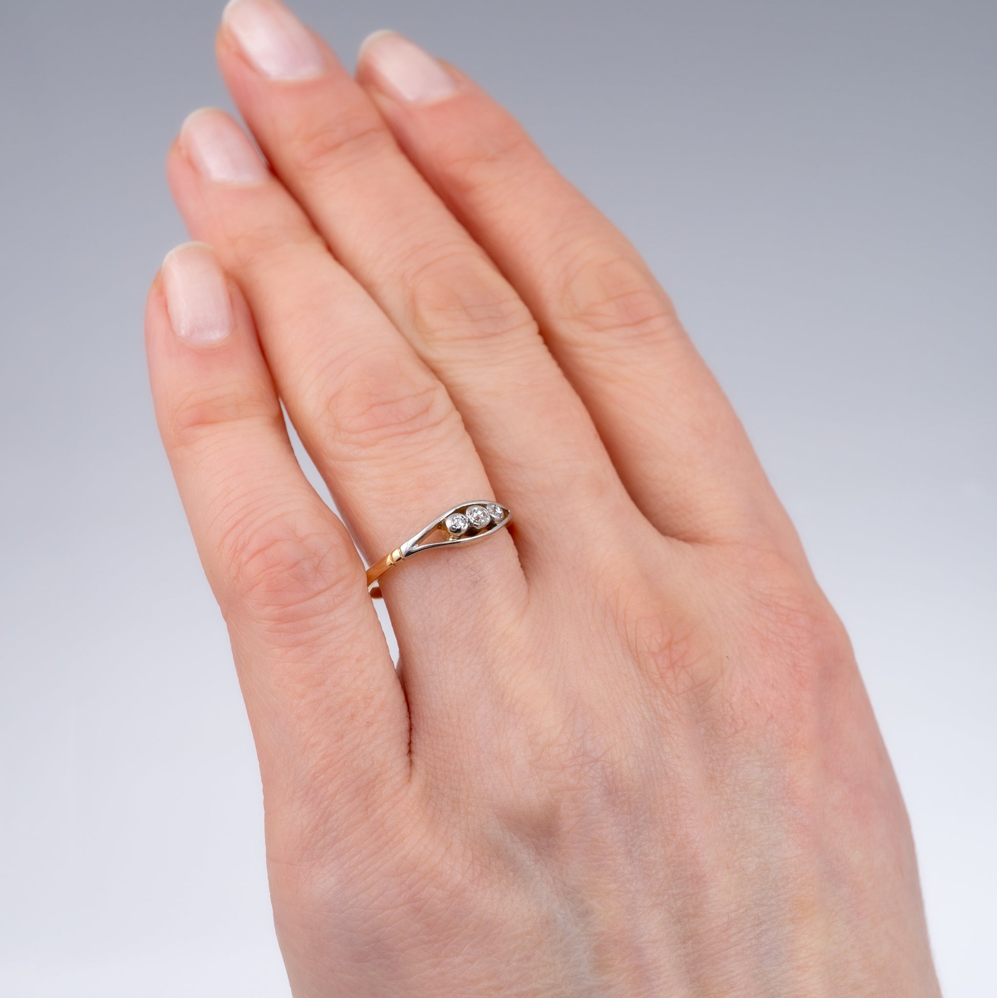 Vintage three-stone diamond ring in 18ct gold, worn on hand, showing elegant design