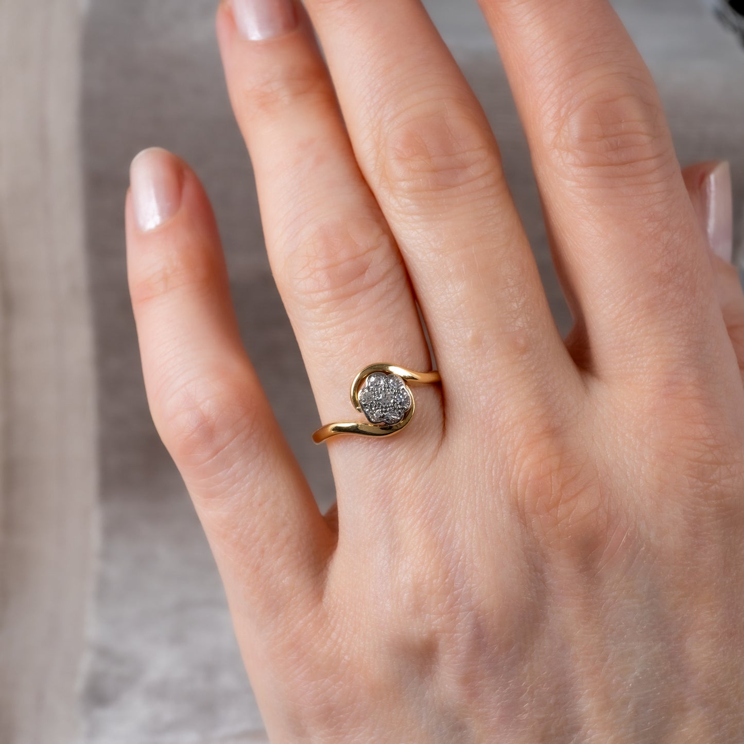 Vintage diamond flower ring in 18ct yellow gold on hand with platinum setting