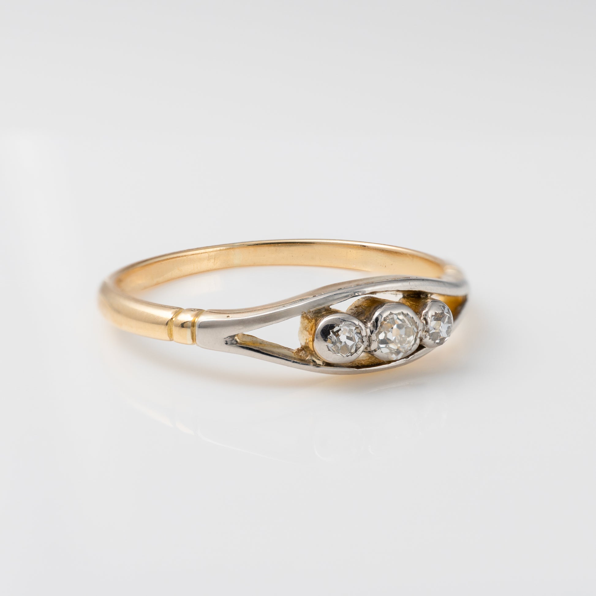 Side profile of vintage three-stone diamond ring in 18ct gold, showing old-cut diamonds in bezel mounts