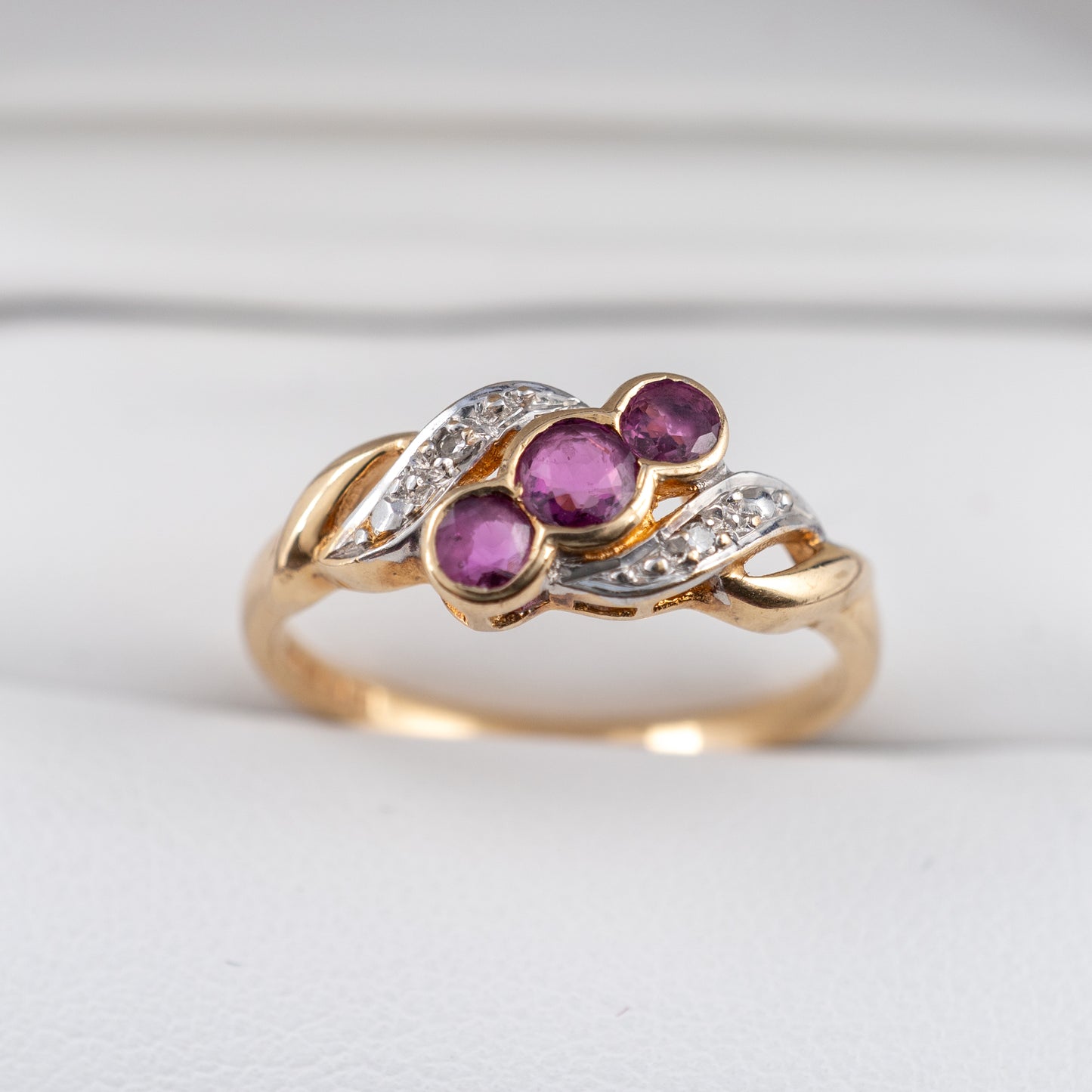 second hand ruby ring with three rubies and diamond accents 