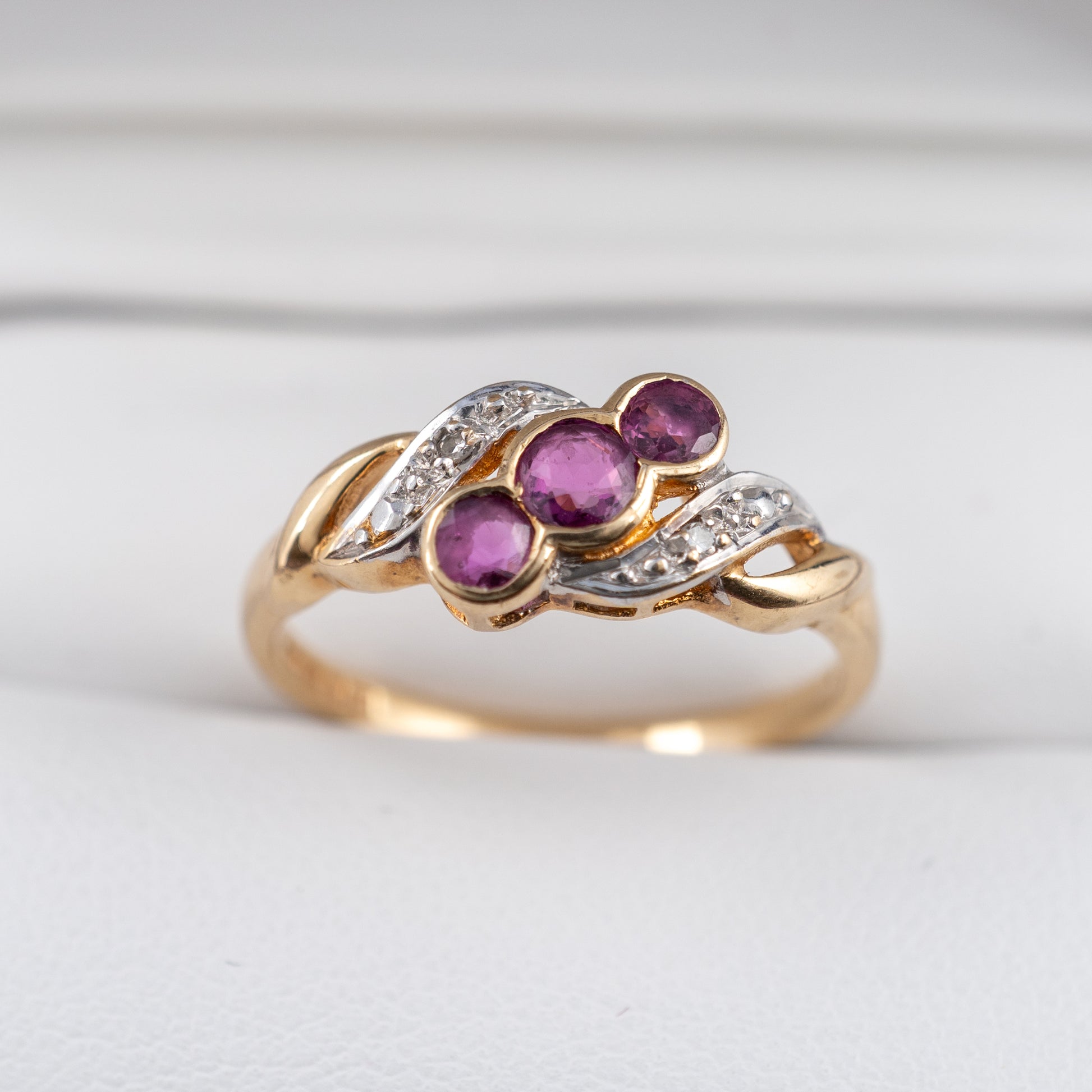 second hand ruby ring with three rubies and diamond accents 