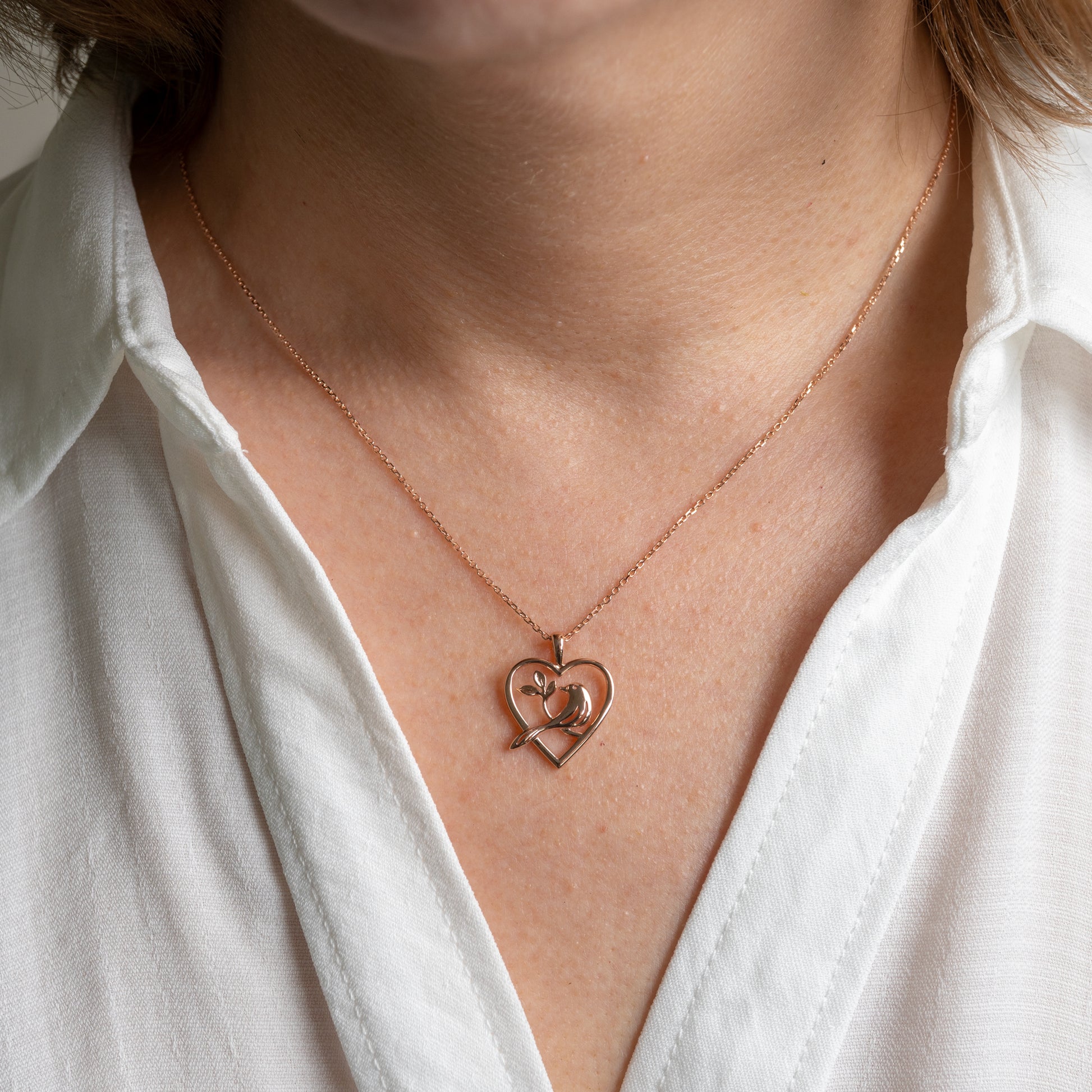 woman wearing 375 rose gold bird in heart necklace by hunters fine jewellery