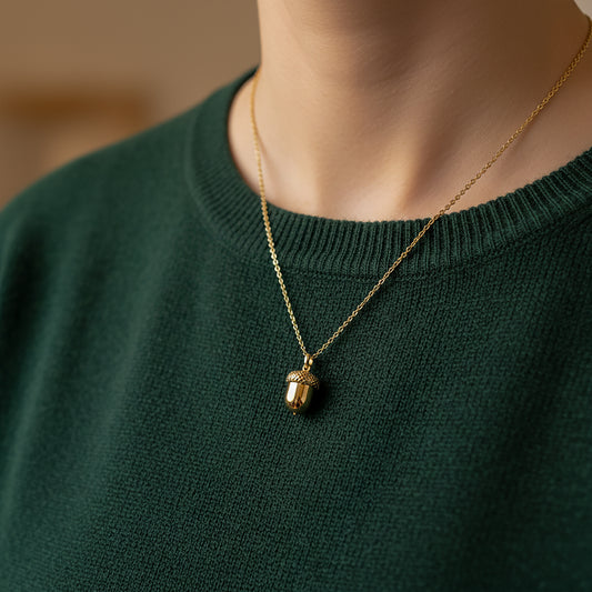 woman wearing dark green jumper with yellow gold acorn pendant