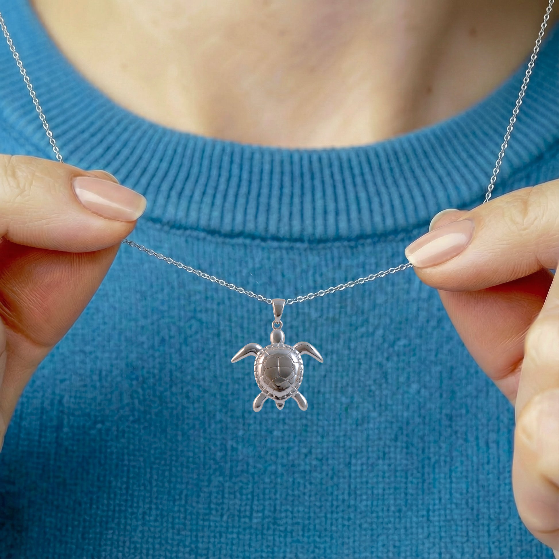 woman wearing silver sea turtle necklace with ocean blue jumper