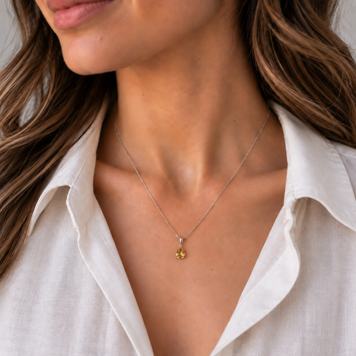 woman wearing a white open shirt and a citrine teardrop necklace