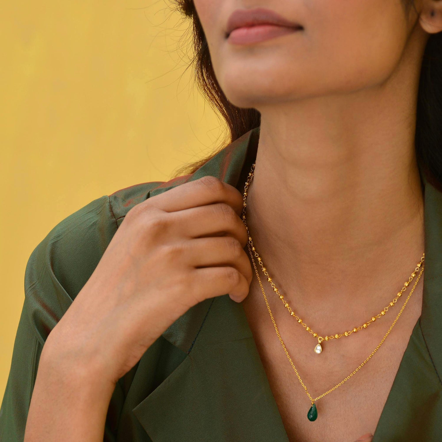 woman wearing gold and emerald necklaces 