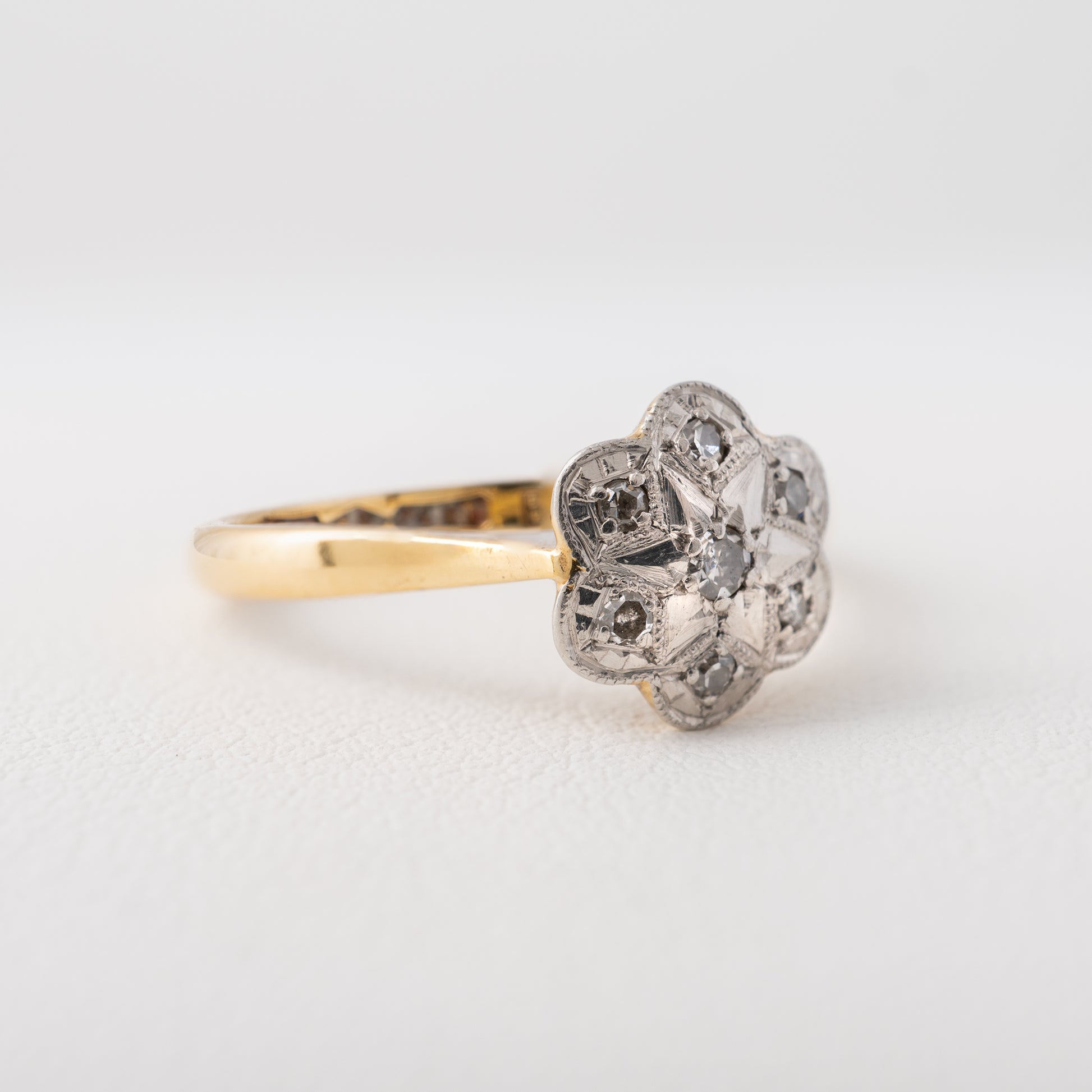 Side profile of vintage diamond daisy ring showing platinum flower setting