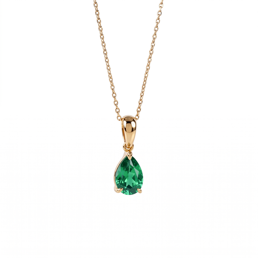 A gold pendant necklace featuring a teardrop-shaped lab emerald gemstone, suspended from a delicate gold chain against a plain white background.