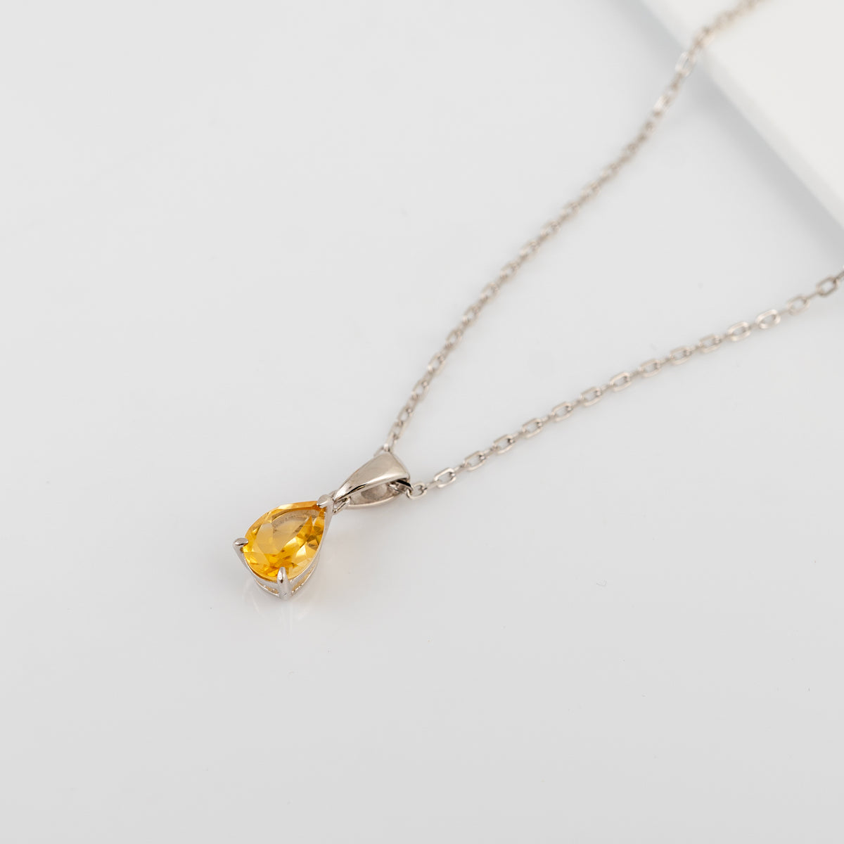 Full view of the natural citrine teardrop necklace and silver chain on a white background.