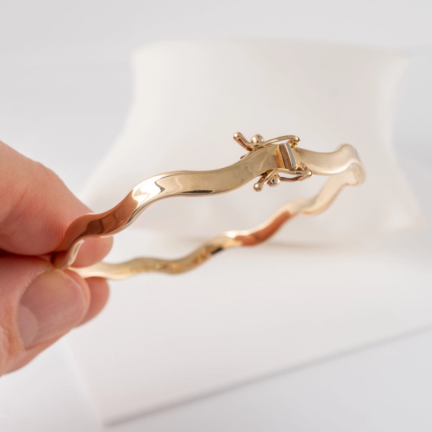 375 gold wave bangle bracelet – close-up of hinged clasp being held.