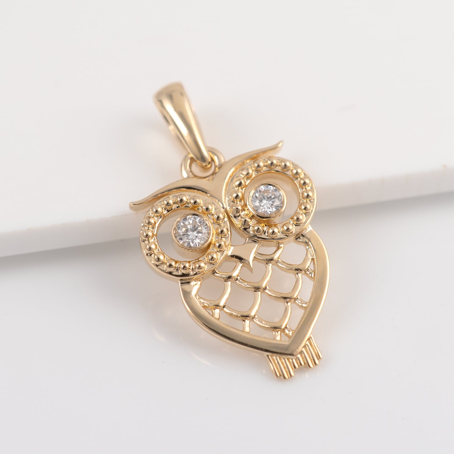 Gold owl pendant with diamond eyes on a white background