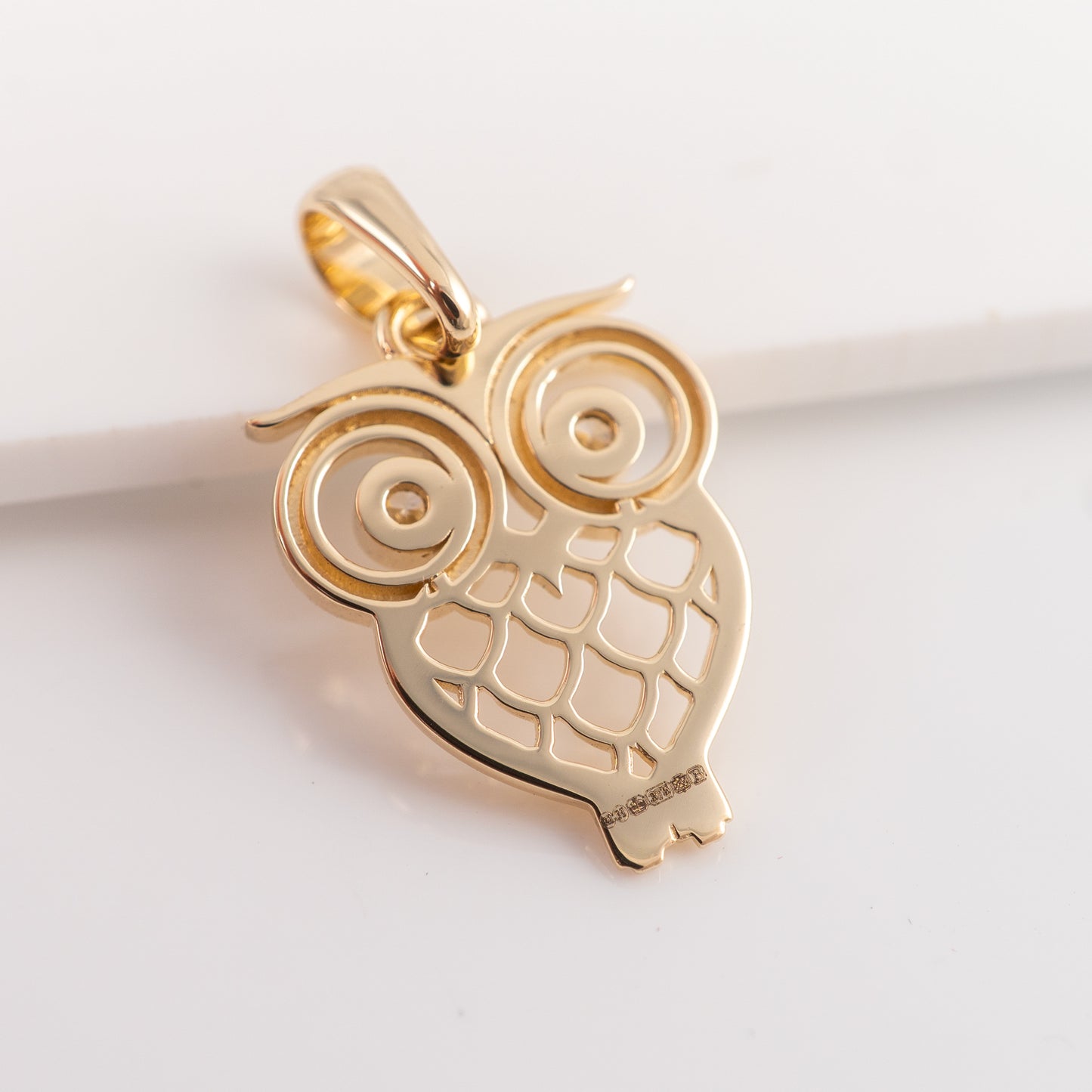 Gold owl-shaped pendant on a light background