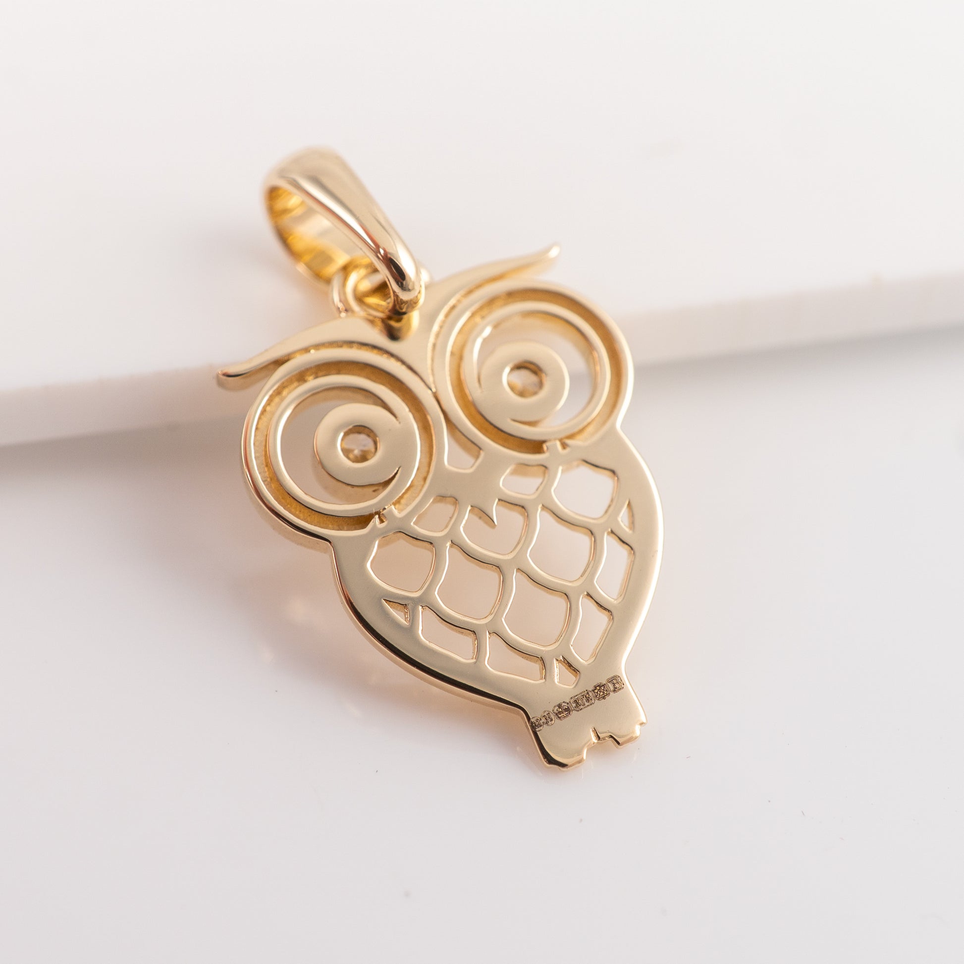 Gold owl-shaped pendant on a light background