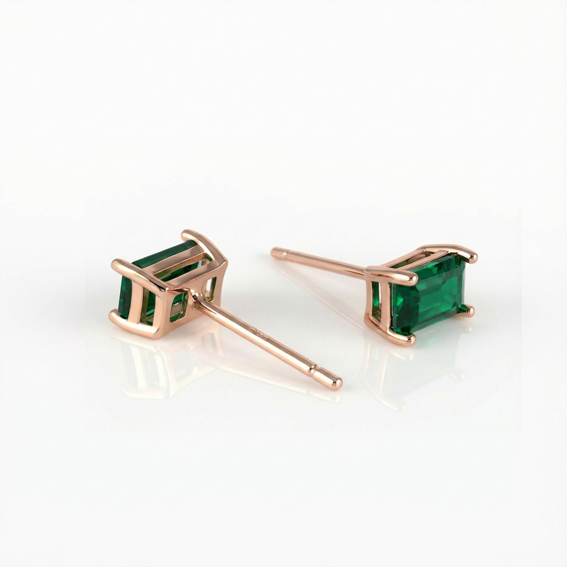 Rose gold earrings with green gemstones on a white background