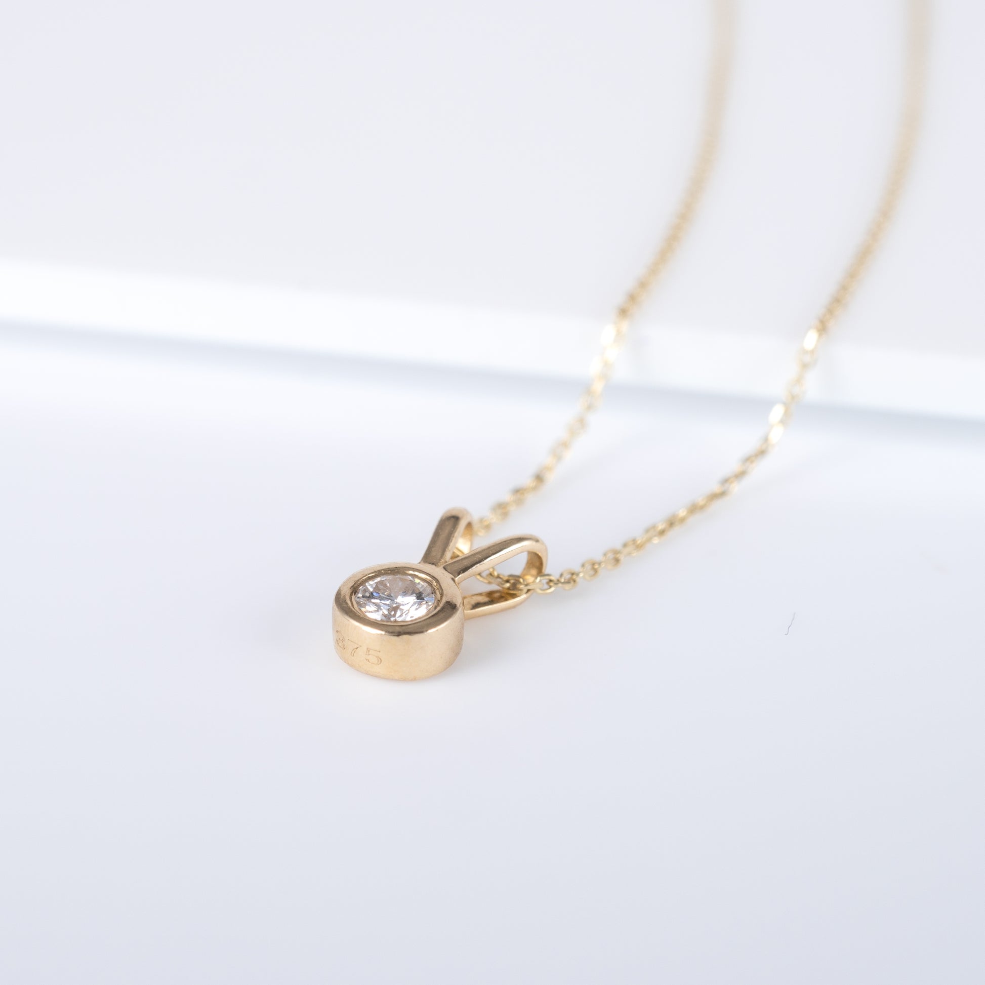 Close-up of 9ct yellow gold lab-grown diamond V bale pendant necklace with visible hallmark - Hunters Fine Jewellery